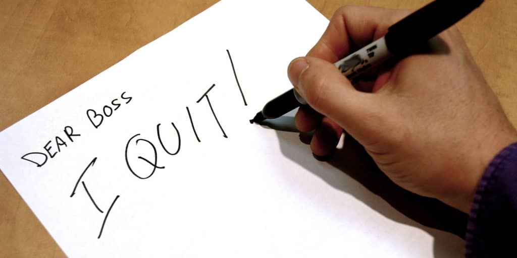 A man writing on a piece of paper to his boss that he is quitting his job.